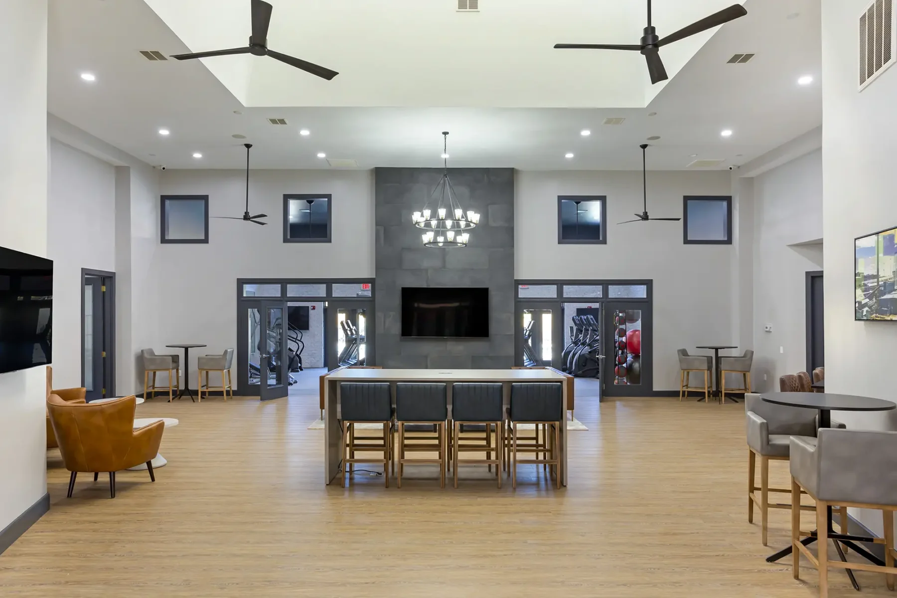 Clubhouse lounge with tables, chairs, sofas, and TVs